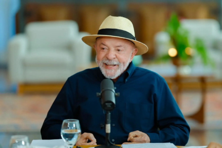 Lula usa chapéu e fala diante de um microfone