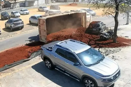 Caminhão tombado com carga de terra espalhada ao lado de carro estacionado no Jardim dos Buritis, em Aparecida de Goiânia
