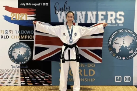 Isabelle Sava posa com medalha diante da bandeira do Reino Unido em campeonato mundial de taekwondo