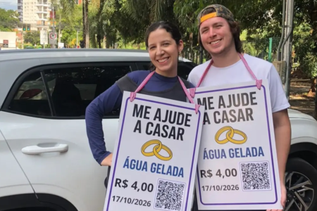 Bruno Melo e Ana Luiza Piaza vendem água gelada no sinal com uma placa sobre o casamento