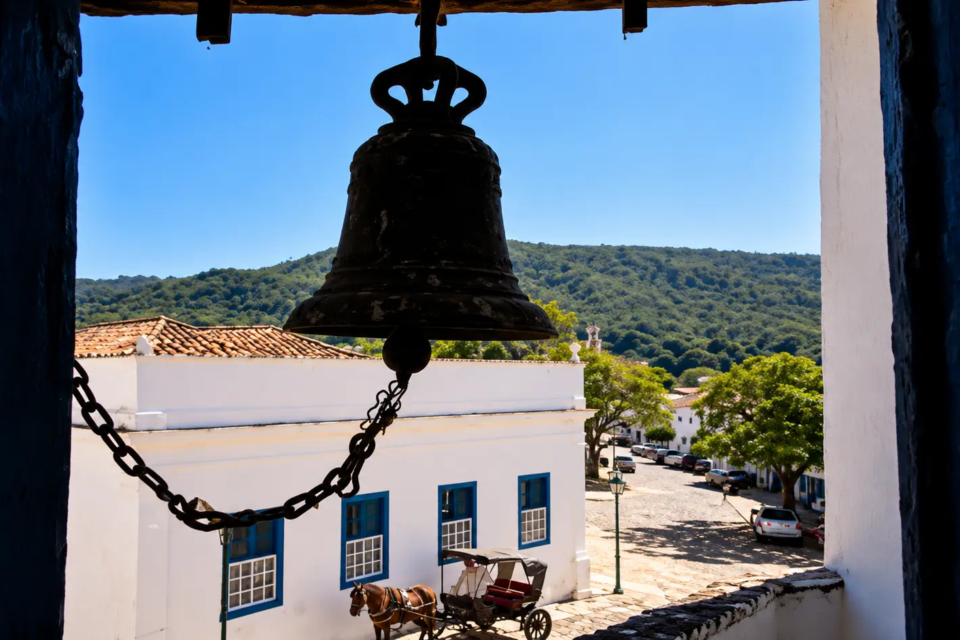 Vista de um sino histórico a partir de uma torre, com casarões coloniais, ruas de pedra e paisagem ao fundo, na cidade de Goiás. (Foto: Glauber Mattos/)